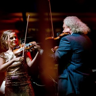 zdjęcie z koncertu Szalone skrzypce i muzyka świata - Muzycy na scenie - kobieta i mężczyzna ze skrzypcami.
