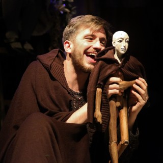 "O mniejszych braciszkach św. Franciszka" - spektakl dla dzieci - Scena ze spektaklu. Aktor trzyma w ręku drewnianą pacynkę.