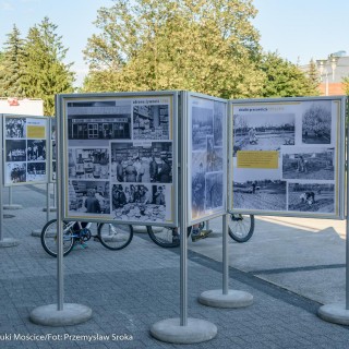 Mościce mam w sercu - wystawa - Stojaki z wystawą zdjęć ustawione na zewnątrz, ludzie na rowerach oglądają je. - Fot. :Przemysław Sroka