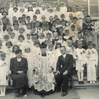 Dzieci pierwszokomunijne wraz z opiekunkami i księdzem. Zdjęcie wykonane na schdach szkoły nr. 8. Z archiwum Grażyny Kisilewicz.